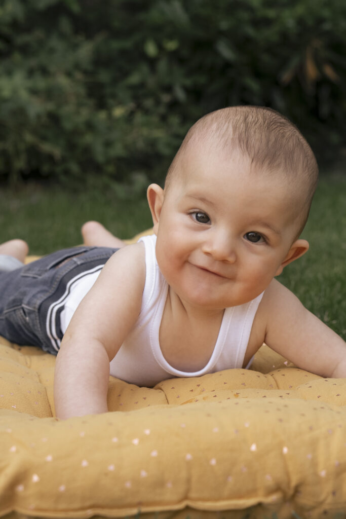 Portrait tendre d’un bébé souriant, réalisé par Claire Stroh, photographe spécialisée en enfance.